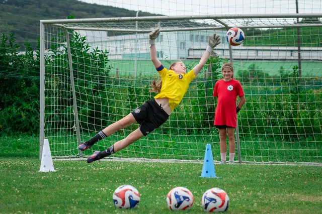 Mladá brankářka ve skoku vyráží míč na brankářském kempu