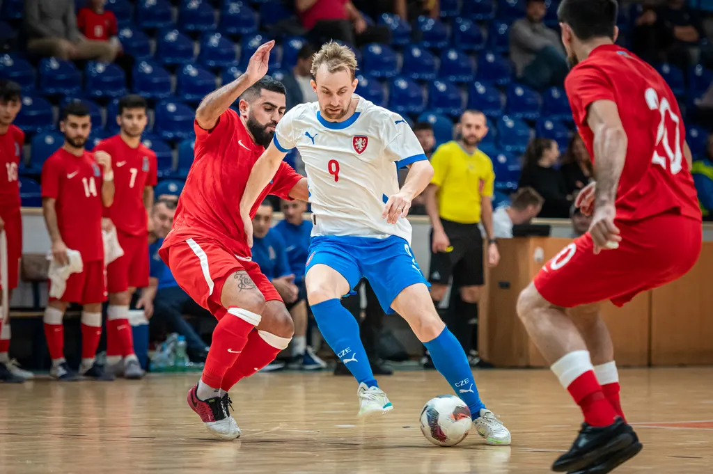 Český futsalový reprezentant vede míč mezi dvěma soupeři