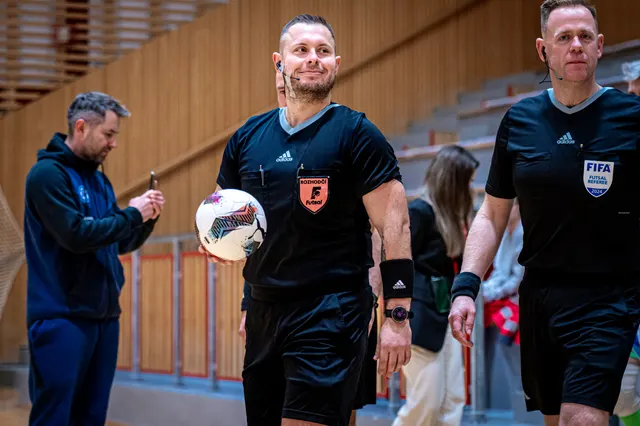 Usměvavý futsalový rozhodčí s míčem před utkáním v hale