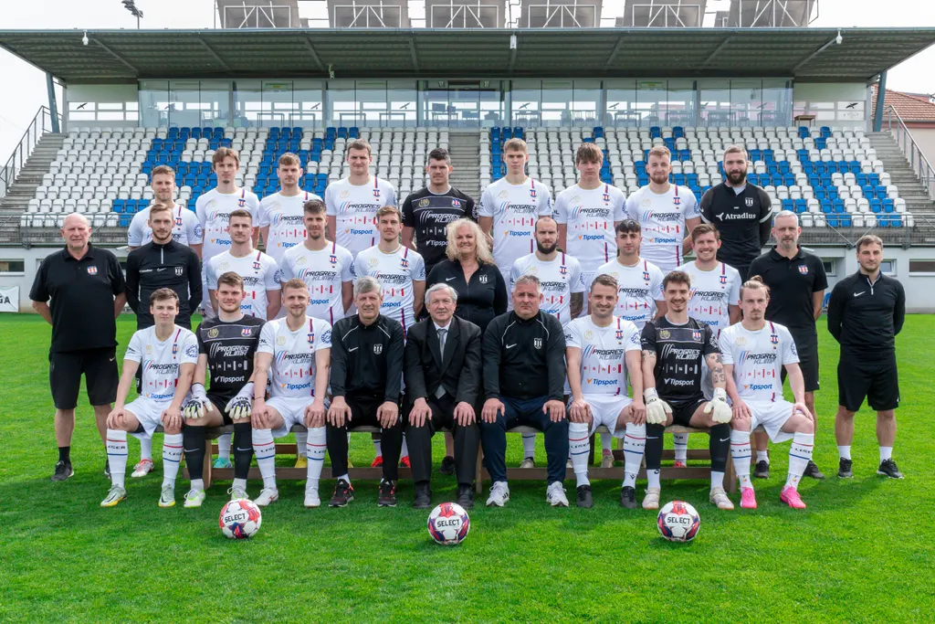 Týmová fotka mužů SK Líšeň v bílých dresech na stadionu